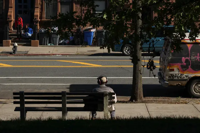 A photo of a man waiting at a bus stop in Harlem